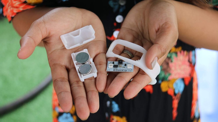 Hands hold a wristband with two button batteries removed that were given out at AFL Grand Final in Brisbane