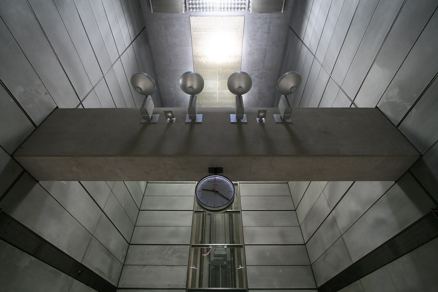 You see a slate grey underground station receiving natural light from above.