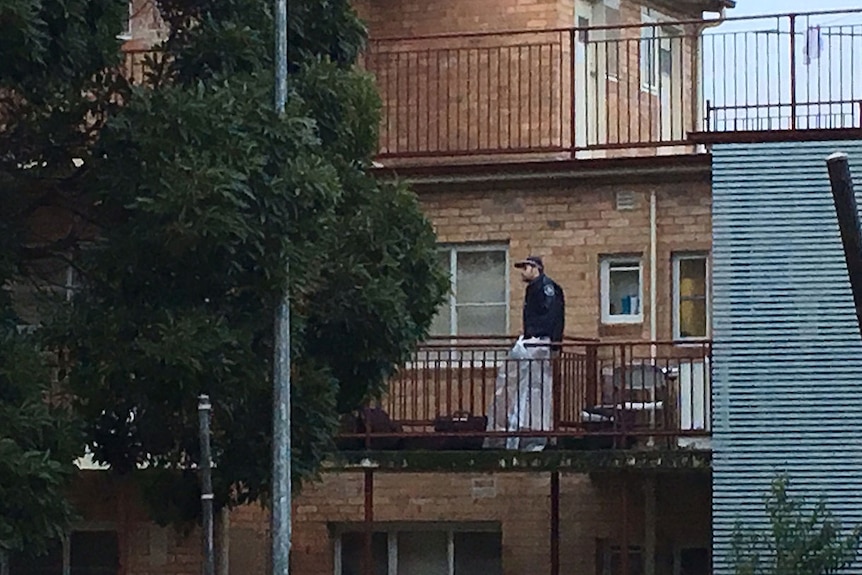 Police officer on a balcony of an apartment believed involved in counter terrorism raids in Melbourne's north.