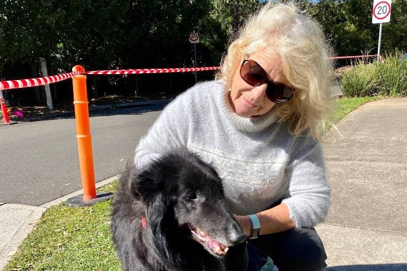 A woman outside kneeling down with a pet doc