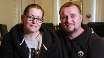 A couple in their home both wearing black hoodie jumpers.