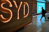 A passenger walks next to a departures sign at Sydney International Airport