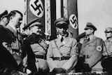 Adolf Hitler (left) stands with a number of senior Nazis iin front of swastika banners.