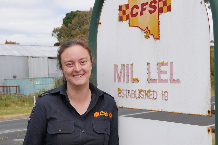 A volunteer firefighter standing next to the sign for the Mil-Lel CFS station
