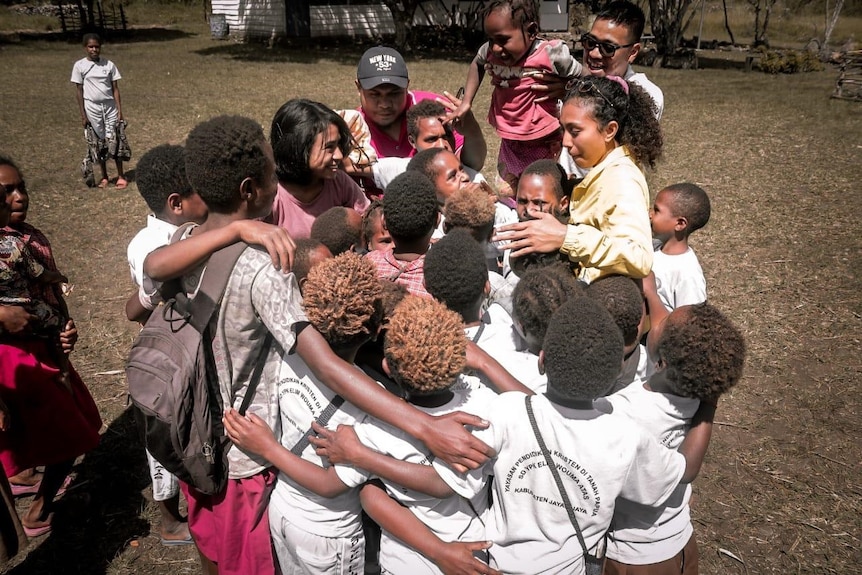 A woman surrounded by students outdoor