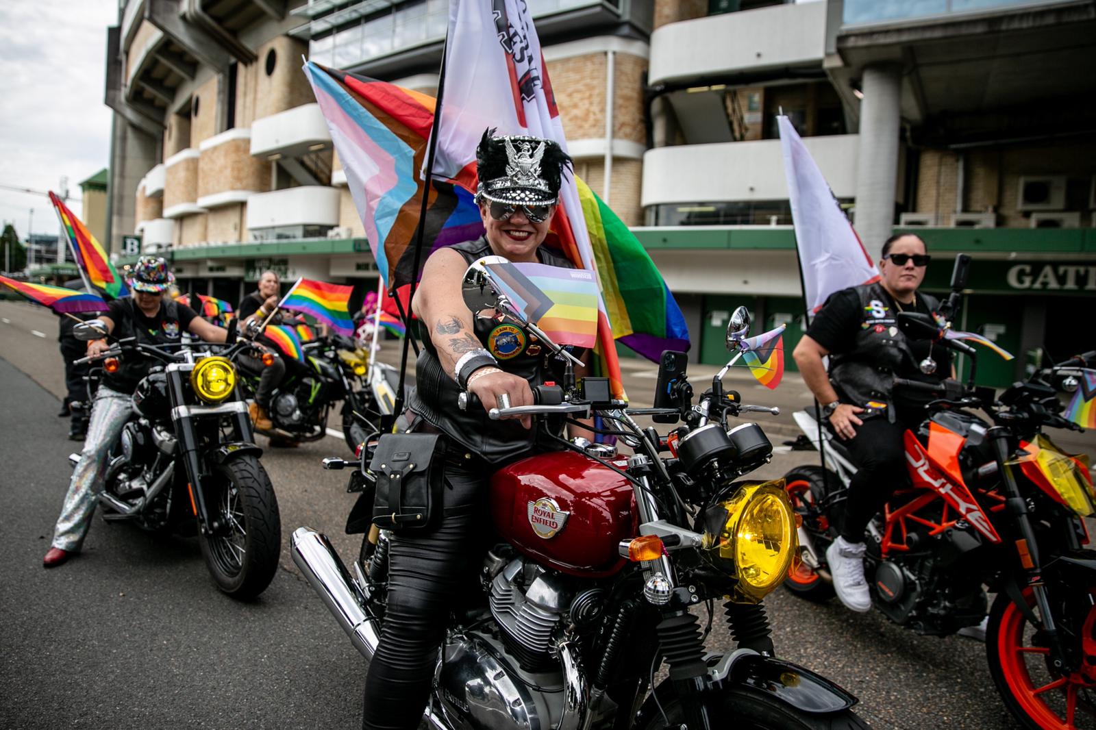 a group of women on bikes some carrying a rainbow flag