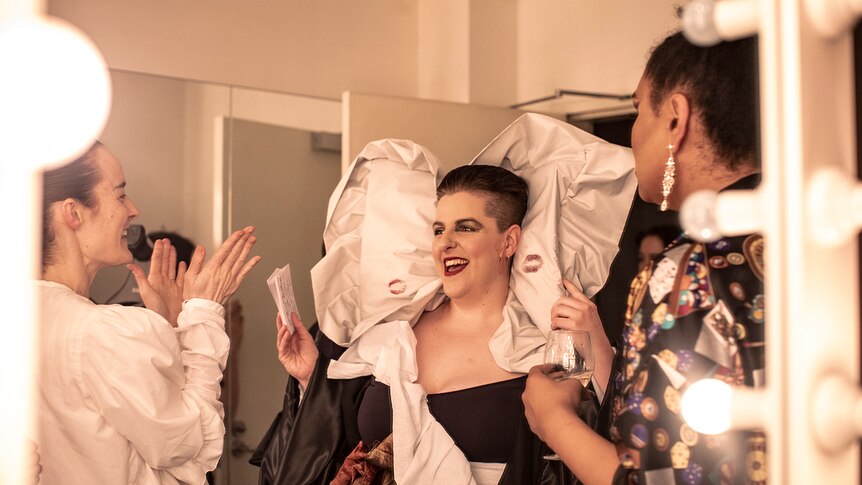 Colour photo of artist Anna McMahon wearing costume and laughing in dressing room.