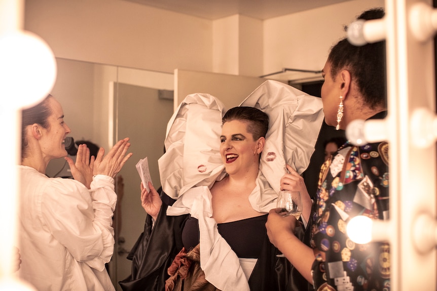 Colour photo of artist Anna McMahon wearing costume and laughing in dressing room.