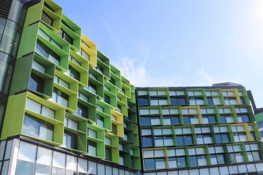 A picture of the exterior of Perth Children's Hospital, showing distinctive green-panelled window frames under a blue sky.