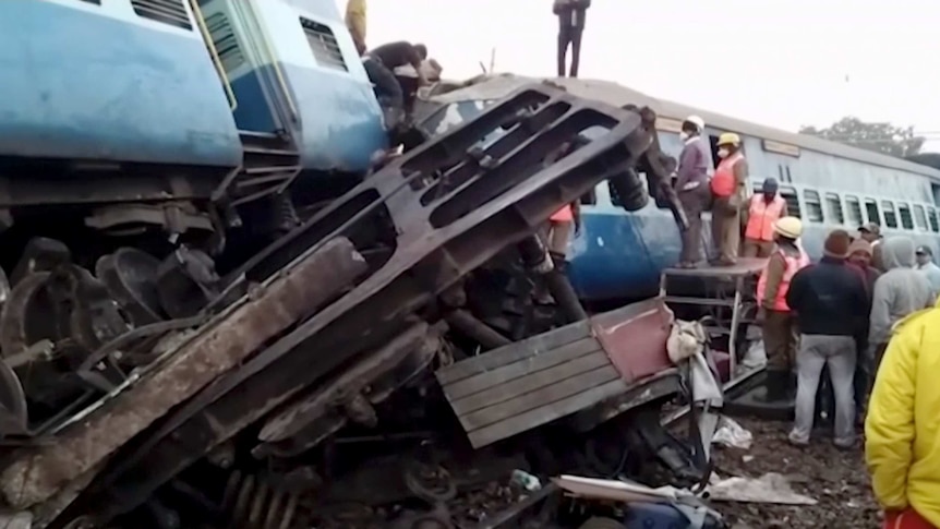 Rescuers stand around coaches of the derailed passenger train.