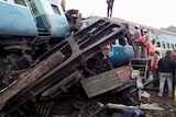Rescuers stand around coaches of the derailed passenger train.