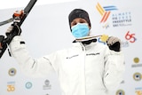 An aerial skier stands with her ski in one hand an a gold medal in the other after a world title.