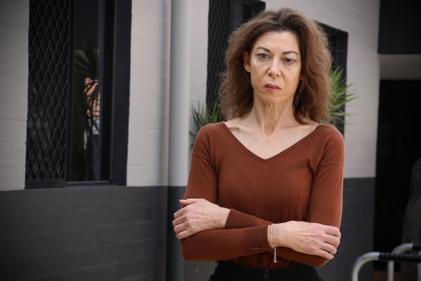 Alison Evans wears a brown top and a solemn expression