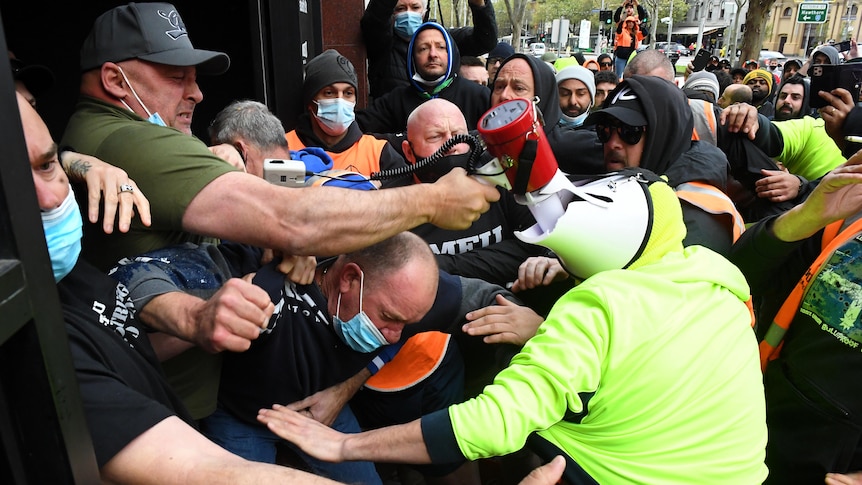 Protestors clash with staff at the entrance of a building