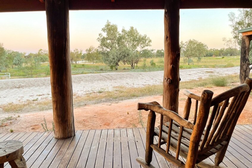 A wooden rocking chair on a veranda overlooking a view of the outback