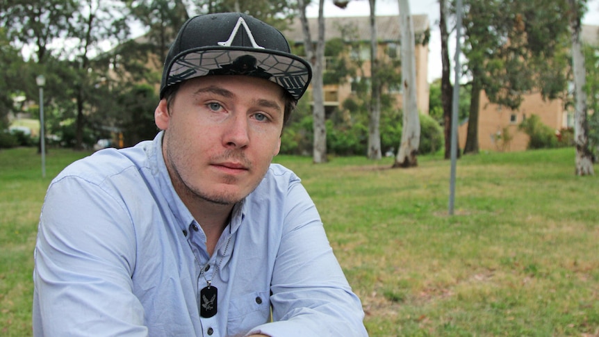 Man wearing a cap sitting at a park bench