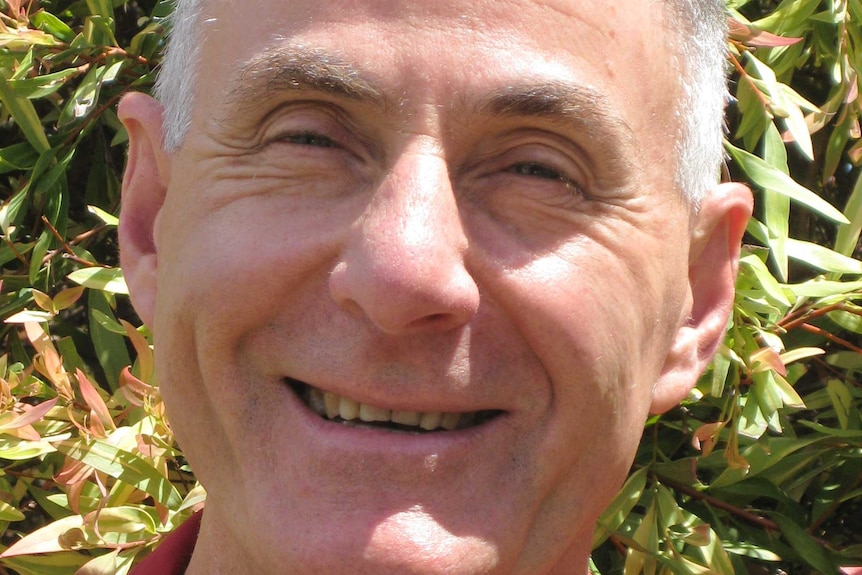 Close-up shot of a man with closely shaved, thinning hair smiling widely.