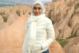 A woman wearing hijab standing in front of rocky hills