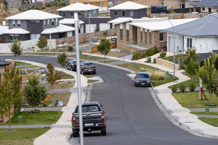 Cars parked on a residential street with newly built homes.