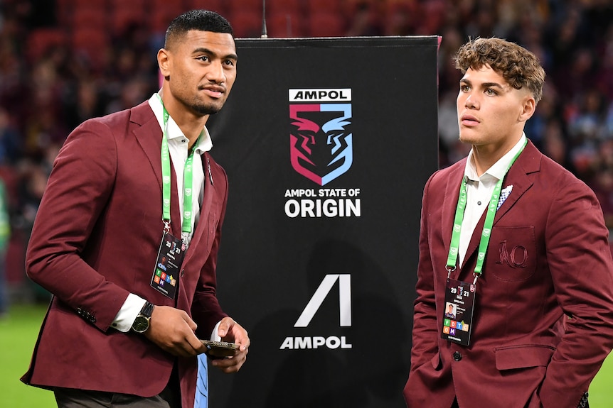 Ronaldo Mulitalo and Reece Walsh stand on the field in Queensland Maroons blazers before State of Origin game two.