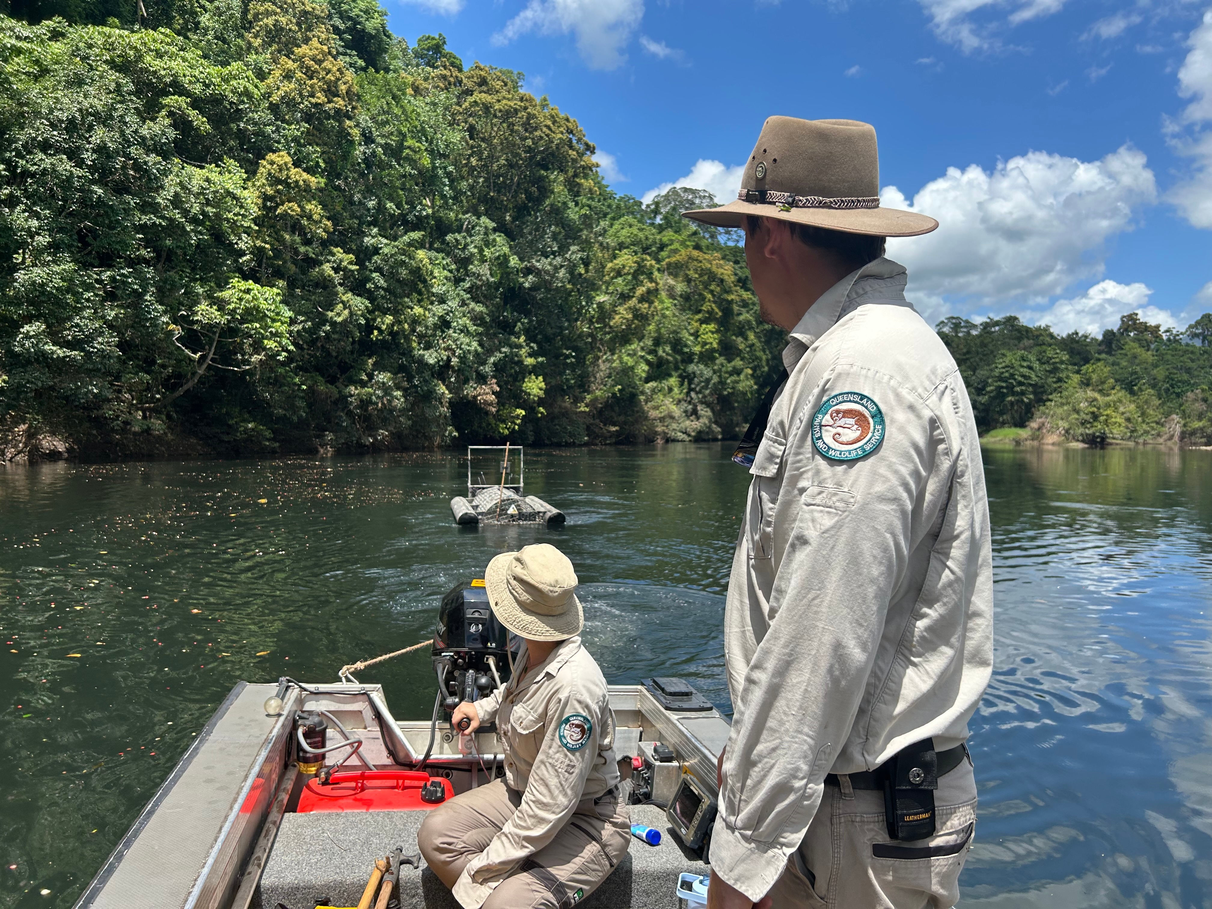 Two people in a boat approach a crocodile trap 