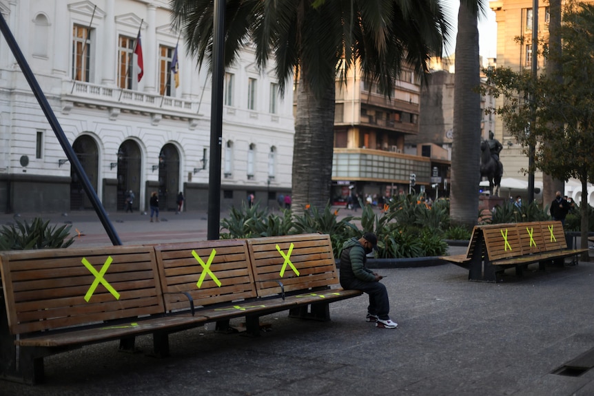 Park benches in a city with Xs on them made with tape.