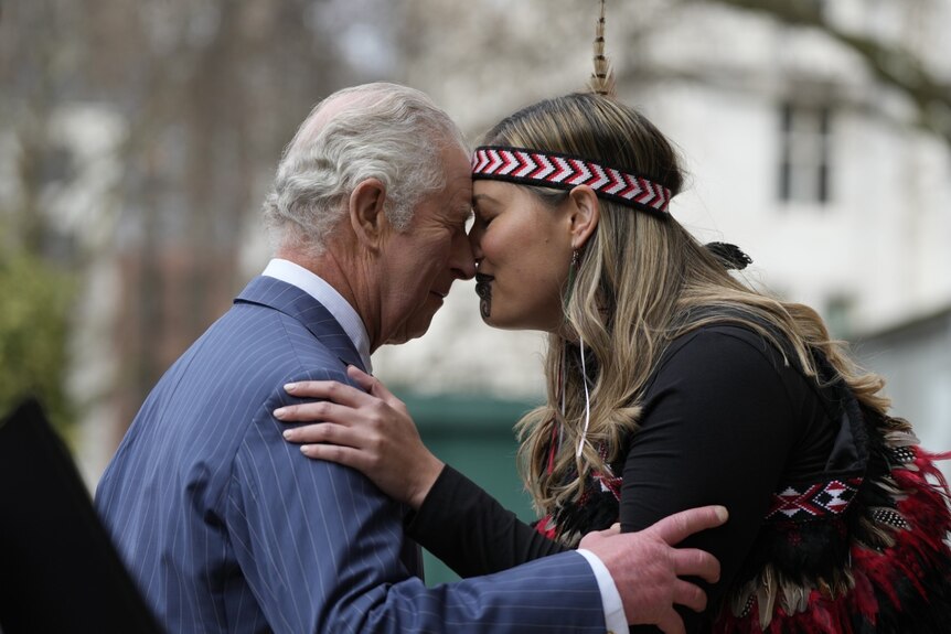 Prince Charles and a woman in traditional Maori dress with facial tattoos press their noses together