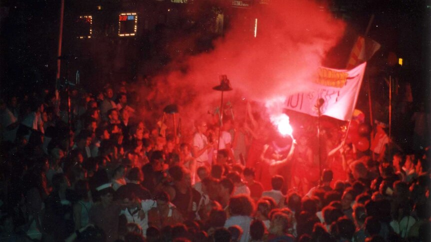 A red flare is lit in the centre of the Mardi Gras parade.