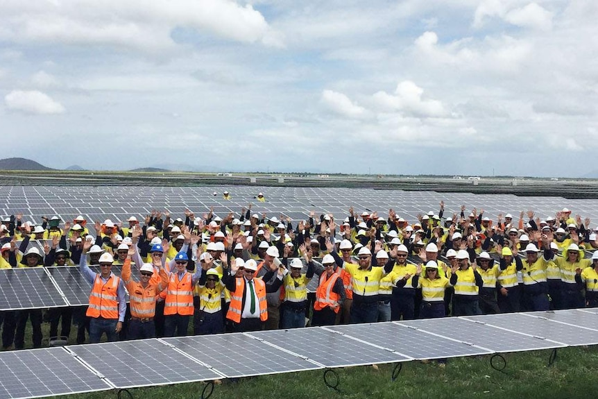 Premier Annastacia Palaszczuk stands in the centre of a large group among hundreds of solar panels in north Queensland in 2017.
