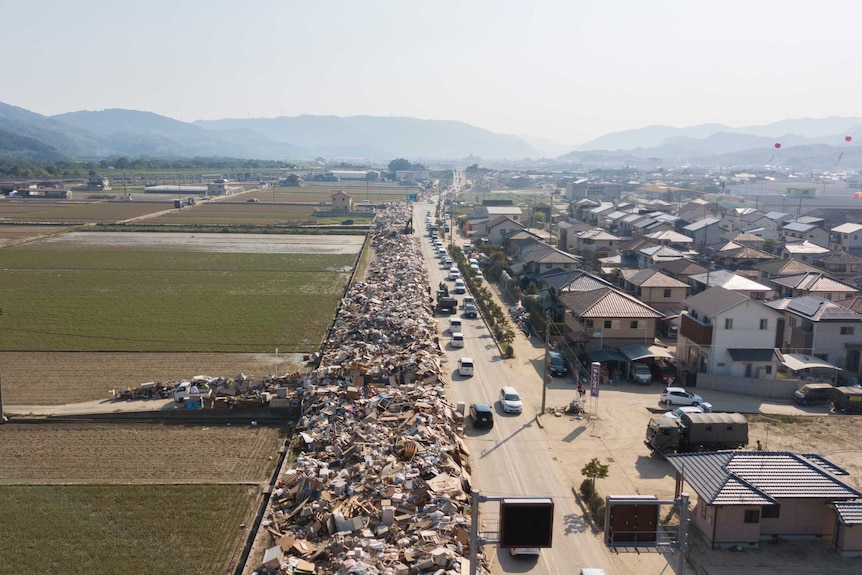 An aerial shot shows rubbish piled up alongside a road for as far as the eye can see.