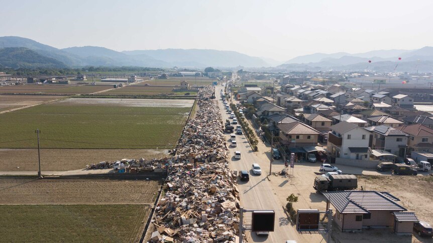 An aerial shot shows rubbish piled up alongside a road for as far as the eye can see.