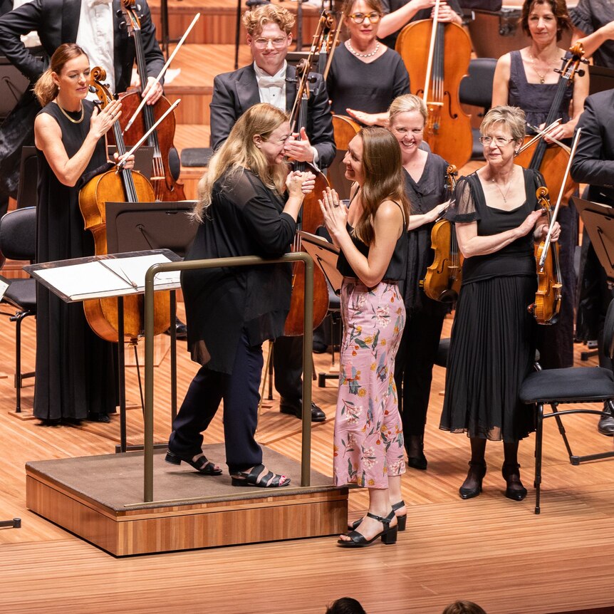 Ella Macens approaches the conductors podium on the stage of the opera house. She is greeted by conductor Simone Young.