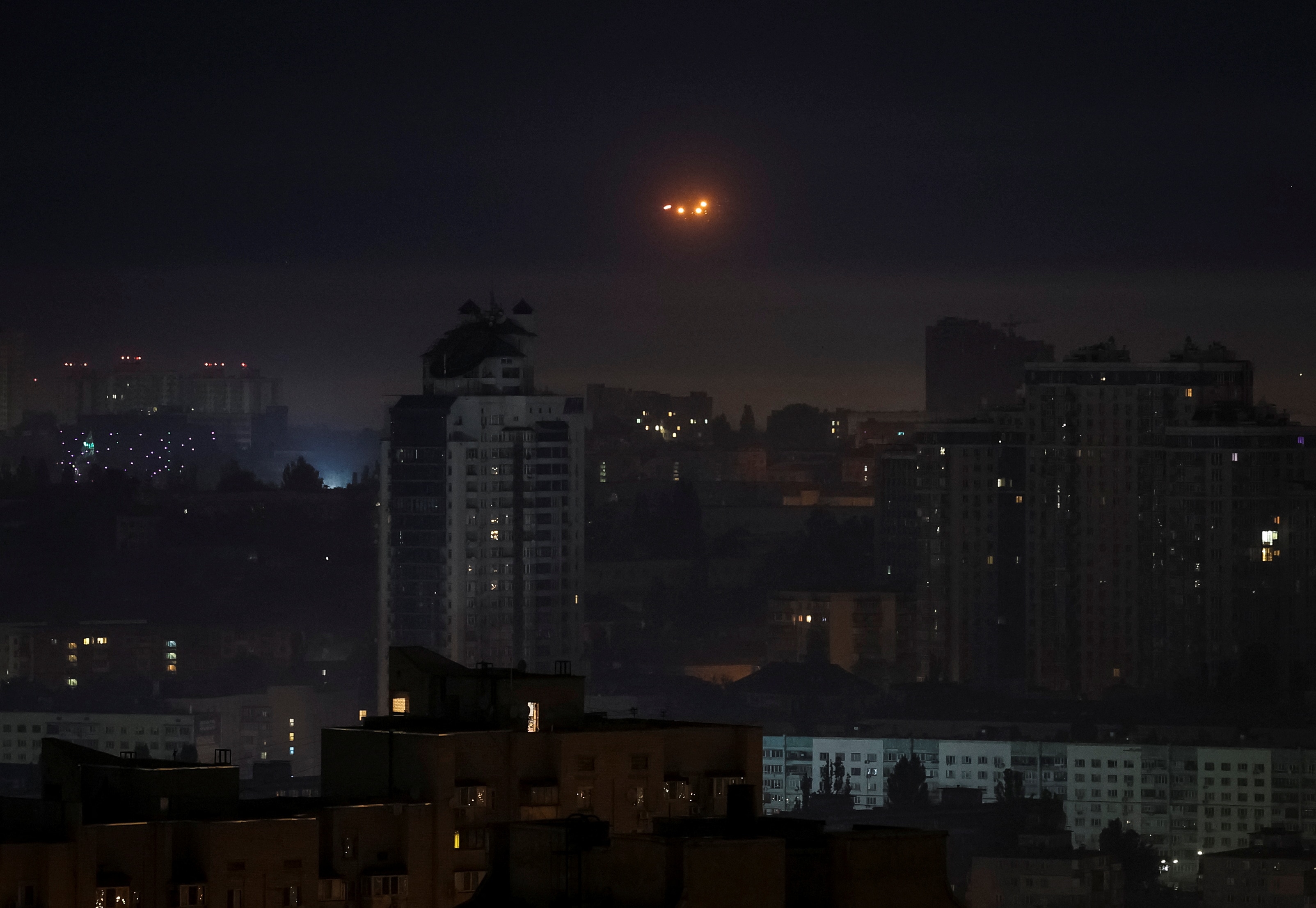 Small orange explosions seen over the nighttime skyline of Ukraine.