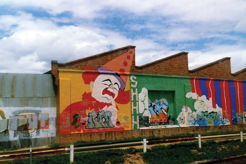 graffiti on a wall with a giant clown painted on it
