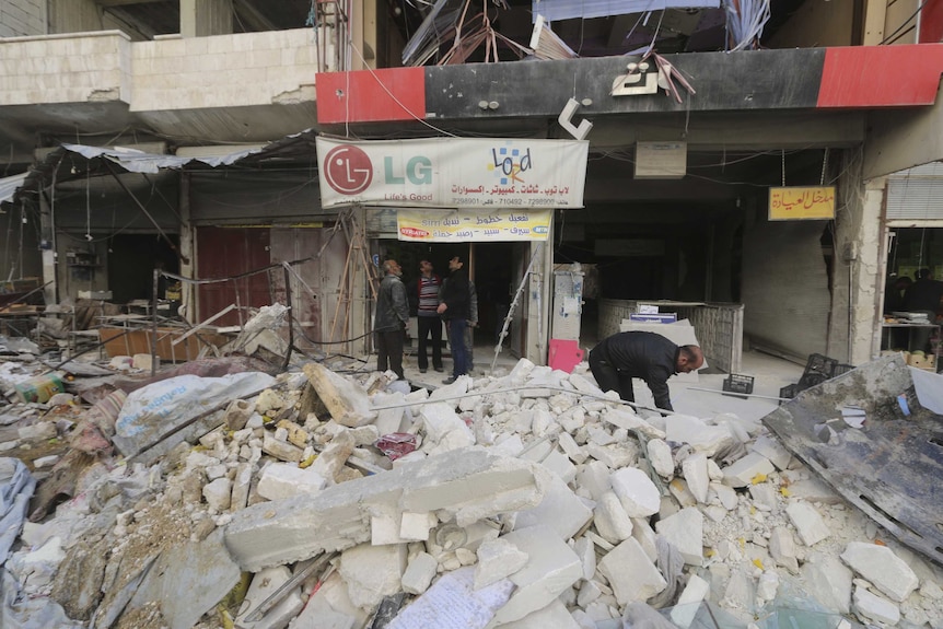 Men inspect damage at claimed site of airstrikes in Ariha, north-west Syria