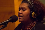 A woman sings into a microphone.