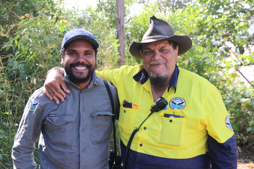 Two smiling men with their arms around each other's shoulders