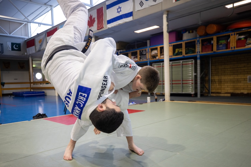 A young boy practicing judo with his coach.