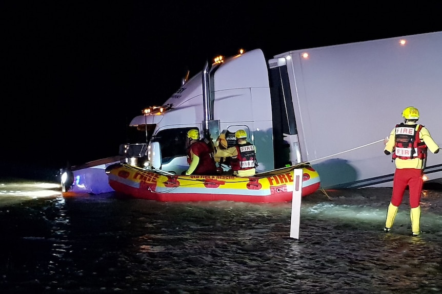 Swiftwater rescue technicians in boat rescue a man after his truck ran into floodwater near Goondiwindi