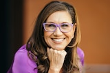 Portrait of Anita Heiss, who is wearing glasses with her chin resting on her fist