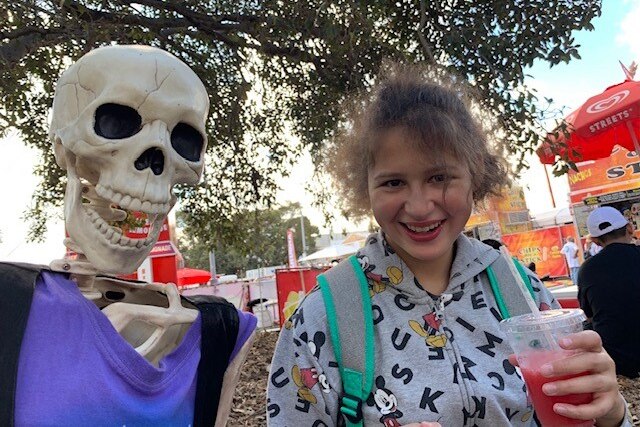 A skeleton in a purple shirt and a girl with brown hair and a slushee, smiling at the camera.