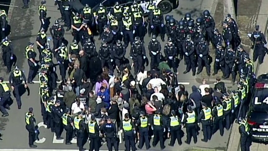 Police officers surround protesters.