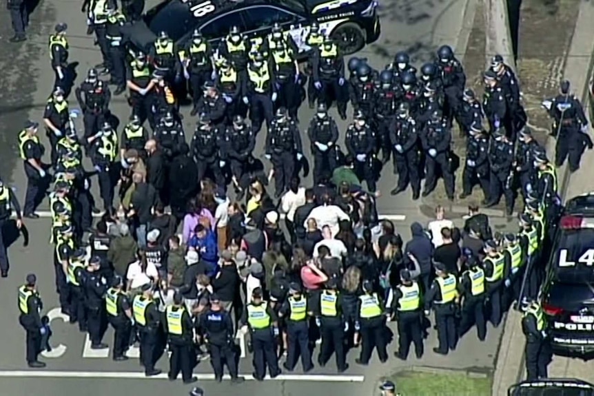 Police officers surround protesters.
