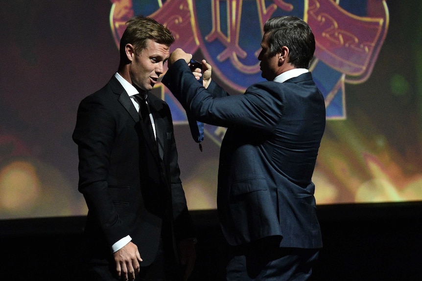 Sam Mitchell (left) is retrospectively awarded the 2012 Brownlow Medal by 1999 Brownlow medallist Shane Crawford.