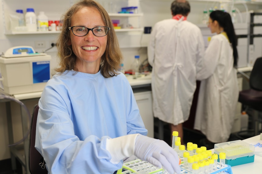 Professor Jennifer Martin pictured in a lab at The University of Newcastle. She is holding some test tubes with gloves on