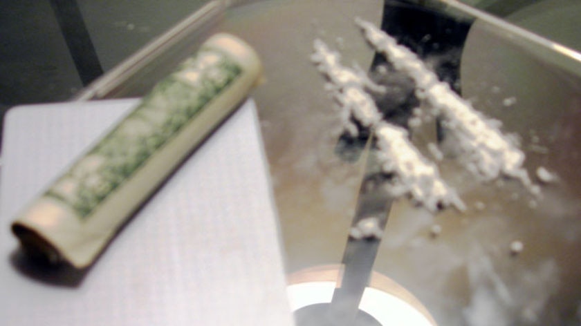 Lines of cocaine and a rolled-up note lie on a glass table.