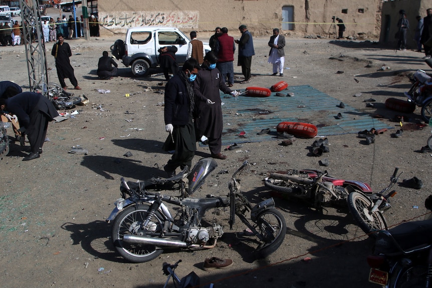 Police examine the site of a bomb blast with debris scattered around. 