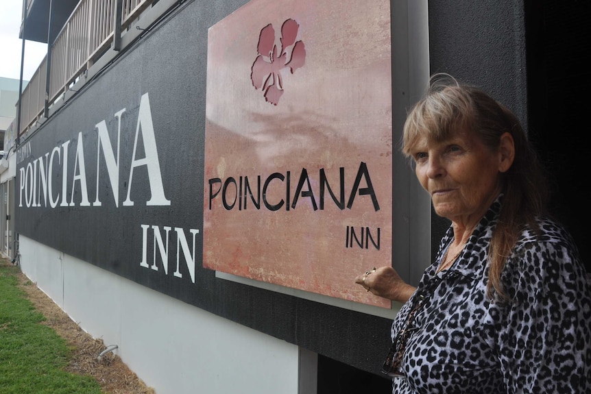 Hotel manager Carol Ford stands next to the sign for her business, the Poinciana Inn.