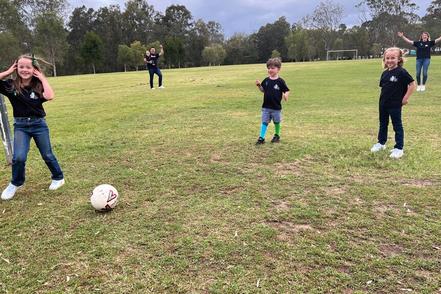 a young family kicking a soccer ball on the field