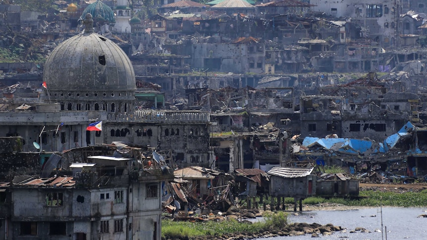 A wide shot of damaged buildings beside a mosque in Marawi city.